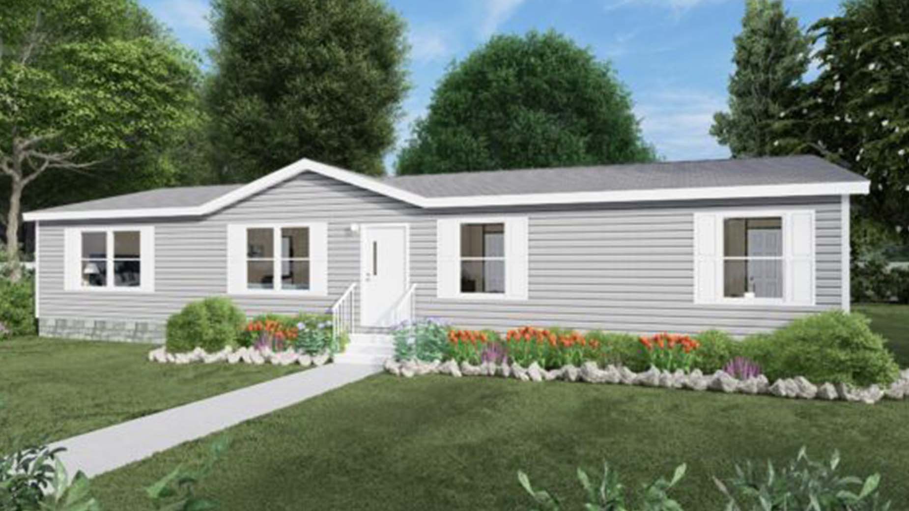 Single-story gray manufactured home with white trim, front steps, flower beds, and trees in the background.